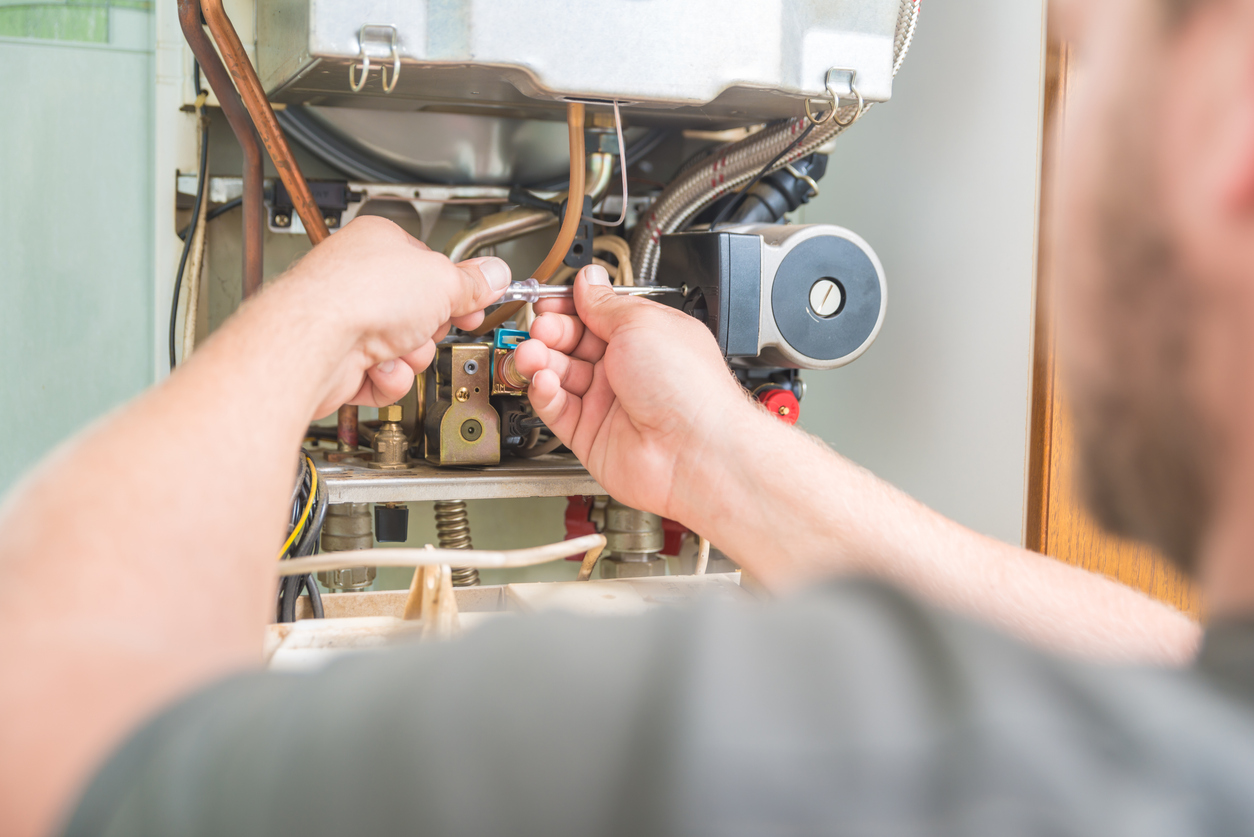 Close-up of a technician using a wrench to work on a furnace during installation.